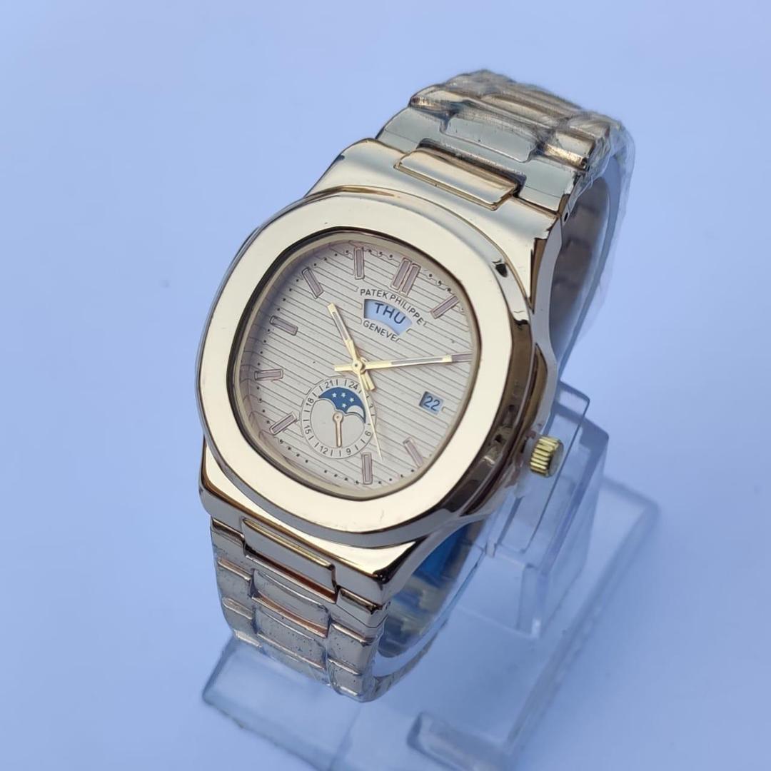 Silver and gold watch on a clear stand with a light blue background
